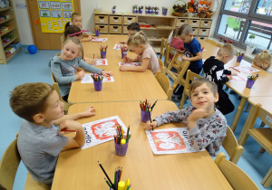 zadowolone dzieci pozują do zdjęcia podczas kolorowania karty pracy